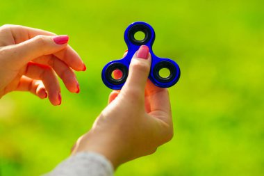 El ile mavi bir spinner oynuyor. Stres giderici oyuncak yeşil 