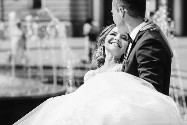 Der Bräutigam hält seine geliebte Braut auf dem Hintergrund der — Stockfoto