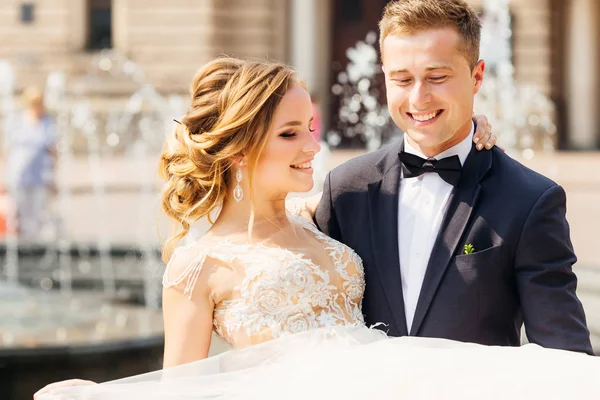 Nahaufnahme eines glücklichen Bräutigams, der seine geliebte Braut mit einer Bohne hält — Stockfoto