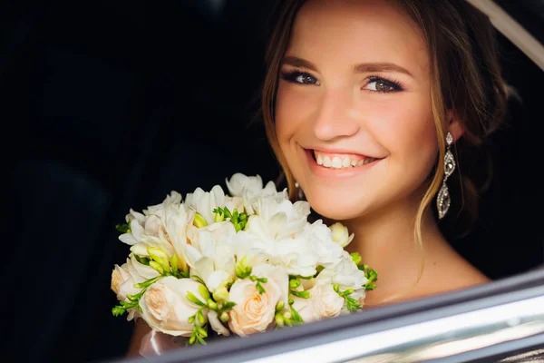 Sorriso sincero di una ragazza con bellissimi gioielli che siede in macchina — Foto Stock