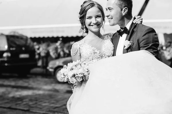 Sonrisas sinceras de los recién casados, el novio mantiene amante en las manos en b —  Fotos de Stock