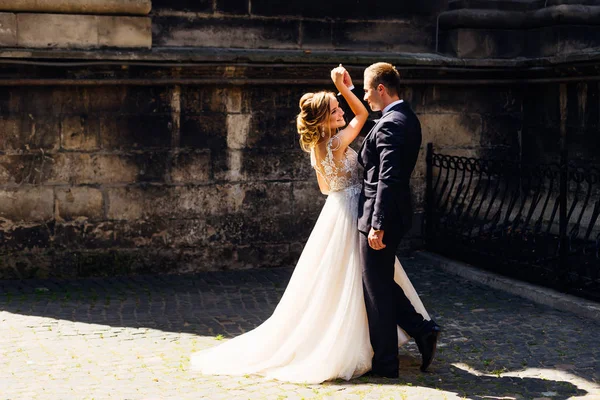 Recién casados bailan sobre un fondo de paredes de ladrillo en una belleza — Foto de Stock