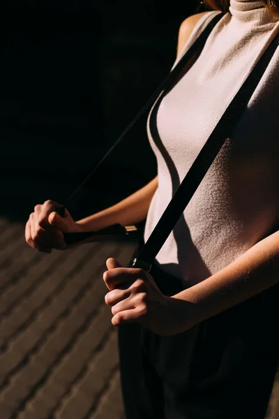 La chica sostiene sus correas de hombro en la calle en el sol —  Fotos de Stock
