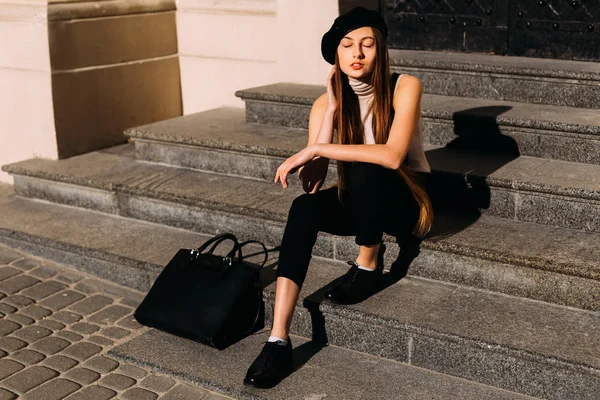 Het meisje in zwarte kleding, zittend op de trap met gesloten haar — Stockfoto