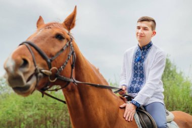Bir at ve gülümsüyor işlemeli gömlekli bir genç bir adam oturuyor