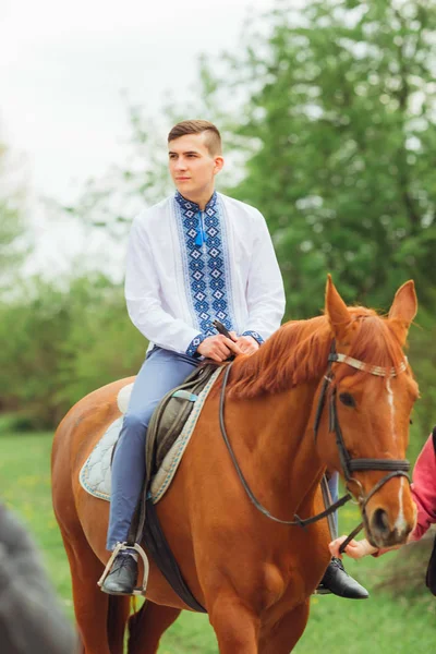 Guy in an embroidered shirt sitting on horseback on the backgrou — Stock Photo, Image