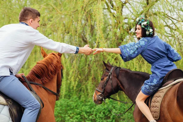 Namorada e namorado estão de mãos dadas e sentados a cavalo — Fotografia de Stock