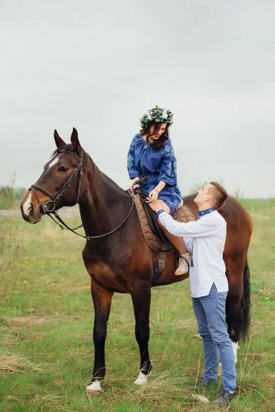 Uma menina com uma grinalda na cabeça sentada em um cavalo e olhando — Fotografia de Stock