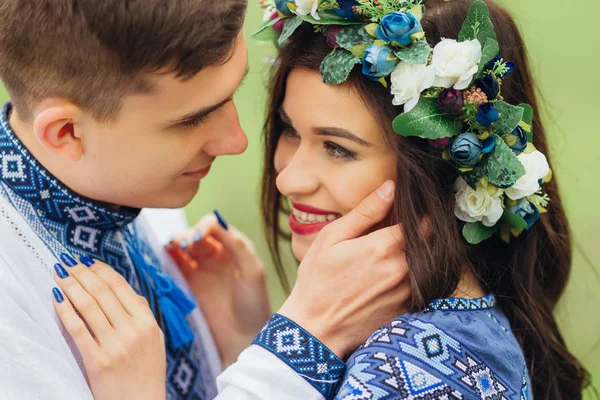 Ein Mädchen mit einem Kranz auf dem Kopf lächelt offen und der Kerl berührt — Stockfoto