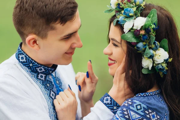 Der Kerl und das Mädchen in bestickten Kleidern schauen einander an. — Stockfoto