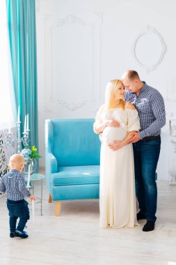 Babası yavaşça hamile anne kucaklayan ve güzel odasında mum Şamdan küçük oğlu görünüyor