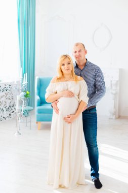 Parlak bir oda içinde başarılı bir koca çocuk için bekleyen karısını kucaklar