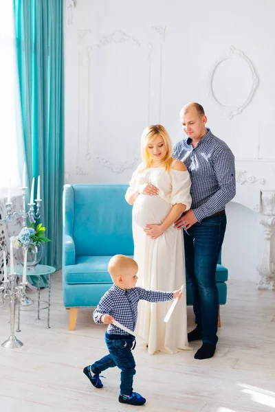 Küçük bir çocuk mumlar ile oynuyor ve harika bir iç ile bir odada hamile anne babası kucaklıyor.