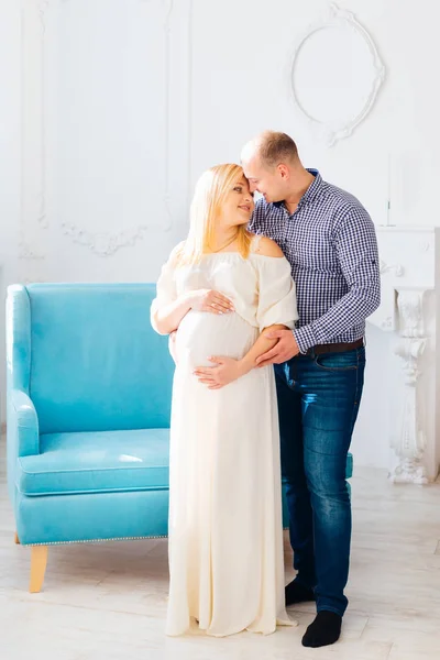 Muž Dívá Svou Těhotnou Manželku Obejme Pozadí Modré Pohovce Bílá — Stock fotografie