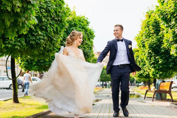 Recién casados caminan y se divierten en medio de una hermosa ciudad —  Fotos de Stock