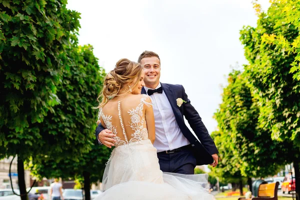 El novio abraza a su novia bonita en un vestido elegante con encaje en el —  Fotos de Stock