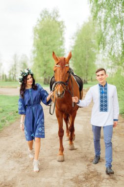 Güzel elbiseli sevgili parkta bir atla yürürken eğlenin.