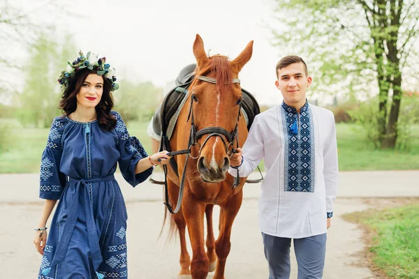 Para zakochanych w uroczysty niebieski odzież trzyma konia za — Zdjęcie stockowe