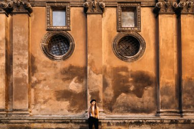 Uzun saçlı güzel bir kız bir yakın duvara yakın duruyor