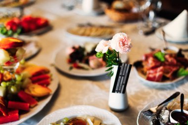 Düğün masa lezzetli yemekleri ve küçük bir vazo Gül