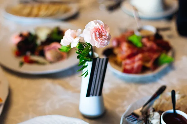 Delikátní růže na svatební stůl mezi lahodné pokrmy — Stock fotografie