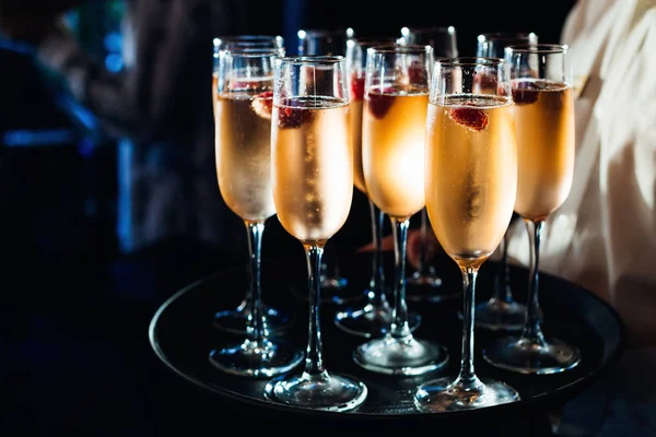 De ober brengt een heleboel glazen champagne en bessen — Stockfoto