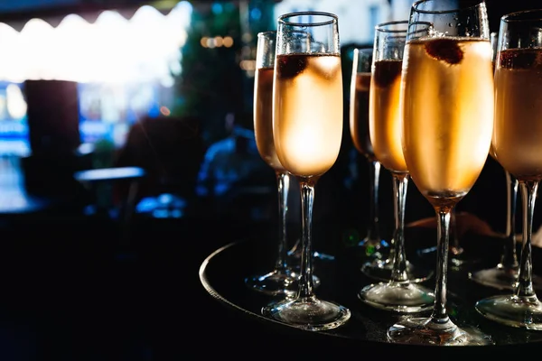 Bicchieri di champagne su un vassoio nella sala buia con raggi di sole sh — Foto Stock