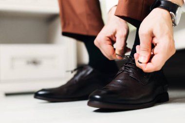 Yatakta oturmuş ve düğün ayakkabıları giyen adam Close-up