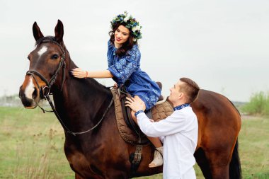 Kız at üstünde oturan ve onu okşayarak ve onun erkek arkadaşı ona tarafından duruyor