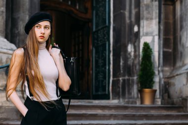  uzun saçlı kız uzak görünüyor ve çantayı arkasında tutar 