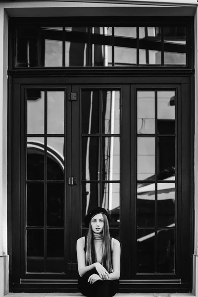 big window and girl sitting on a window sill on black and white