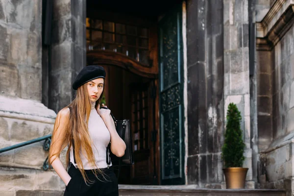 Ein Mädchen hält ihre Handtasche auf dem Hintergrund eines Gebäudes mit einem — Stockfoto