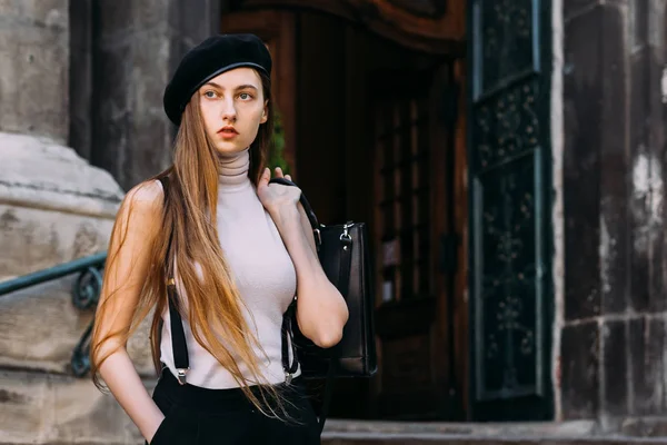 Girl with long hair looks distant and holds the bag behind the — Stock Photo, Image