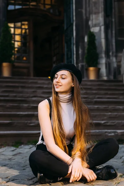 The girl is sitting on the pavement and smiles on the background — Stock Photo, Image