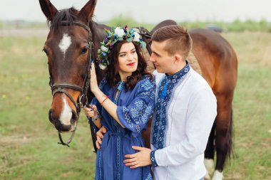 Kız bir at a at başlığı için tutar ve onun erkek arkadaşı onun yanında duruyor ve ona sarılarak
