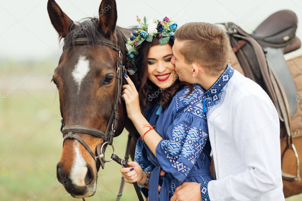 The boyfriend kisses his girlfriend who smiles genuinely and holds the horse for a bridle
