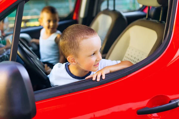 Dois rapazes sentados ao volante de um carro vermelho. condutores jovens . — Fotografia de Stock