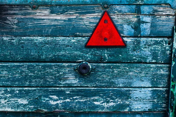 Un piccolo triangolo rosso su una superficie di legno con una vecchia vernice — Foto Stock