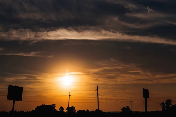 Belo pôr do sol e silhuetas de outdoors e um pilar com — Fotografia de Stock