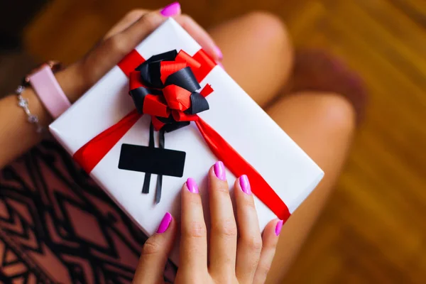 on the knees a girl has a big box with a gift. the box with a ribbon and a bow
