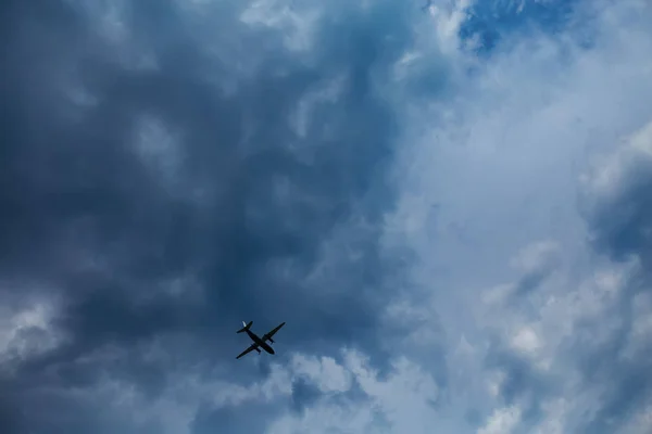 dark blue sky with clouds and an airplane flying in bad weather