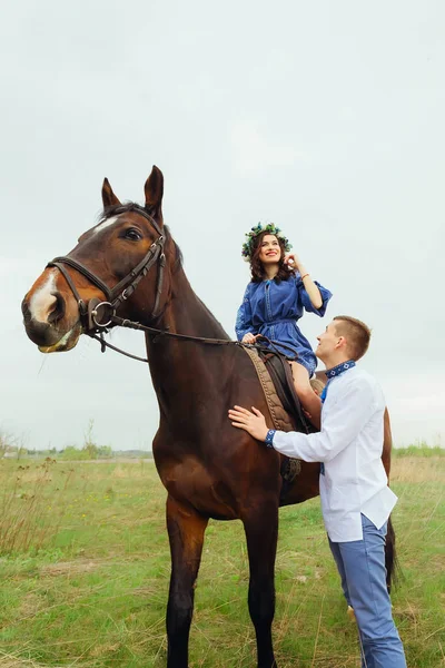 幸せな女の子 馬に座っていると 彼氏が彼女を見て彼女の隣に立っています — ストック写真