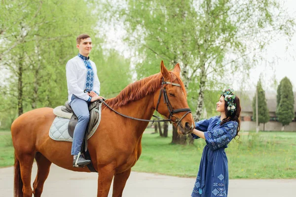 Menina em roupas festivas mantém um cavalo para um freio em um cavalo si — Fotografia de Stock