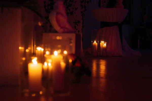 Wysokie świece w szklanych kolb w ciemnym pomieszczeniu. Okrągły stół z — Zdjęcie stockowe