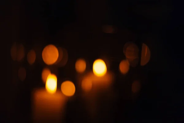 Sagome sfocate di candele che bruciano in una stanza buia — Foto Stock