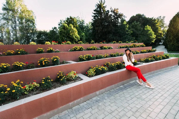 Flickan sitter nära den multilevel blomma sängen och ser på den — Stockfoto