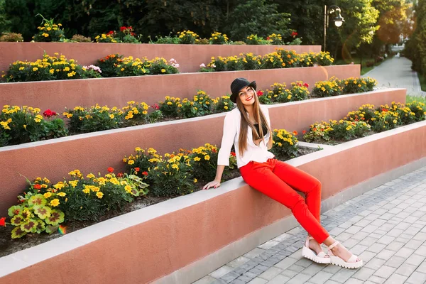 Meisje met een mooie glimlach zit in de buurt van een multilevel flowerbed — Stockfoto