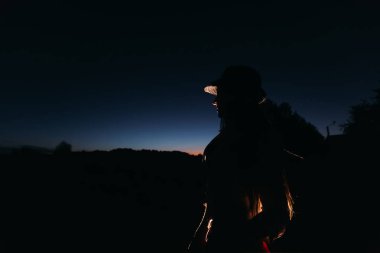 Bir el ba karşı bir kemer üzerinde tutarak şapkalı kız siluet