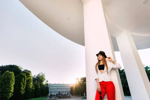 Eleganta pose av en ung flicka som står nära kolumner och holdi — Stockfoto