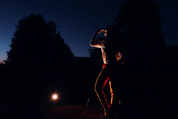 Hora de la noche y la luz artificial que brilla sobre una chica en un sombrero — Foto de Stock